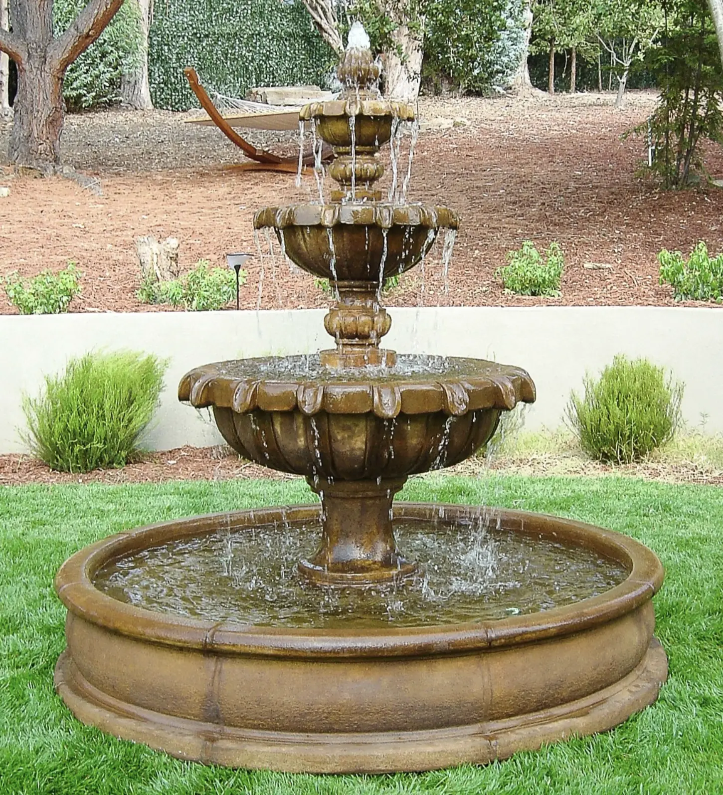 Large multi-tier concrete fountain in a wide circular basin on an estate lawn
